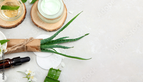 Aloe vera slices and moisturizer on a light background.