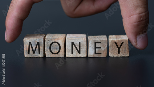 A hand catching the wooden box with money text on the black background, money bank and finance concept