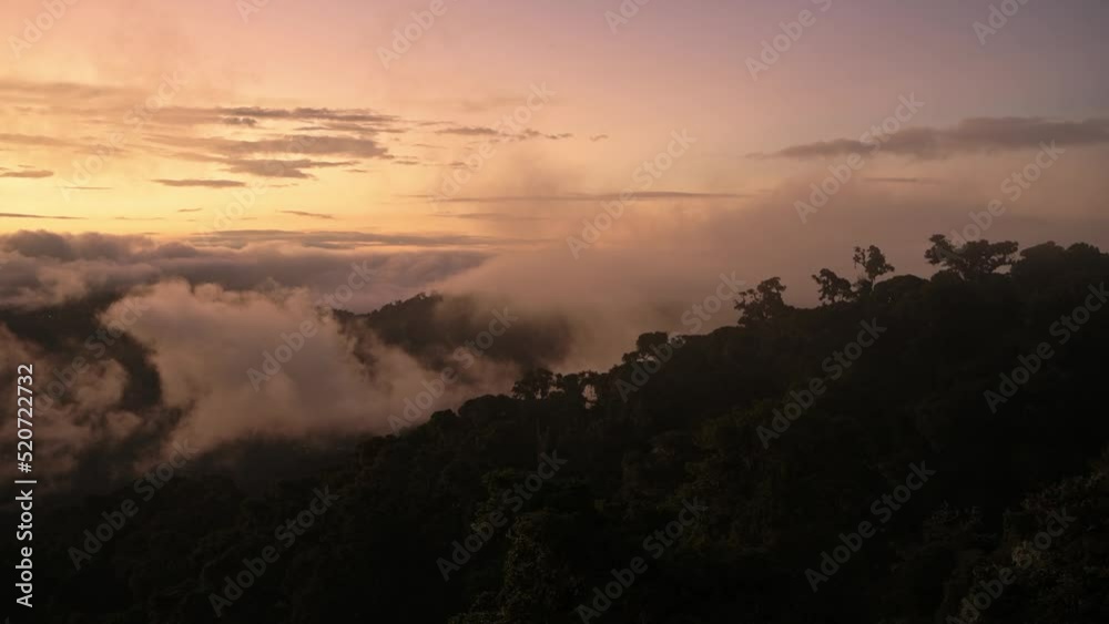 Costa Rica Misty Rainforest Landscape with Mountains and Low Lying Mist and Clouds Rolling Through Valley in Orange Sunset Dramatic Beautiful Light, Los Quetzales National Park Costa Rica Misty Rainforest Landscape with Mountains and Low Lying Mist and Clouds Rolling Through Valley in Orange Sunset Dramatic Beautiful Light, Los Quetzales National Park