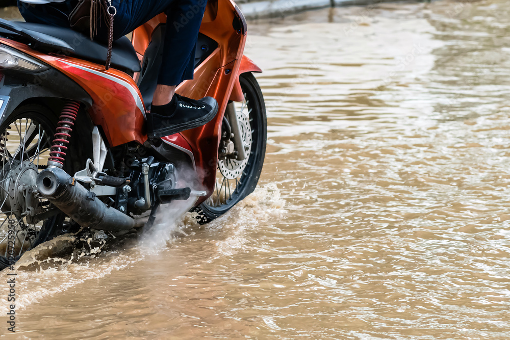 Man ride motorcycle passing through flooded road. Riding motorbike on
