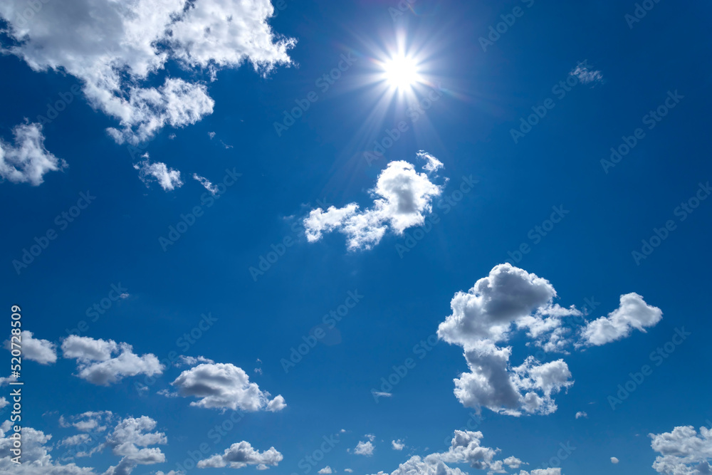 Blue sky with clouds and sun. Bright sun with clouds on blue sky in sunny summer day.