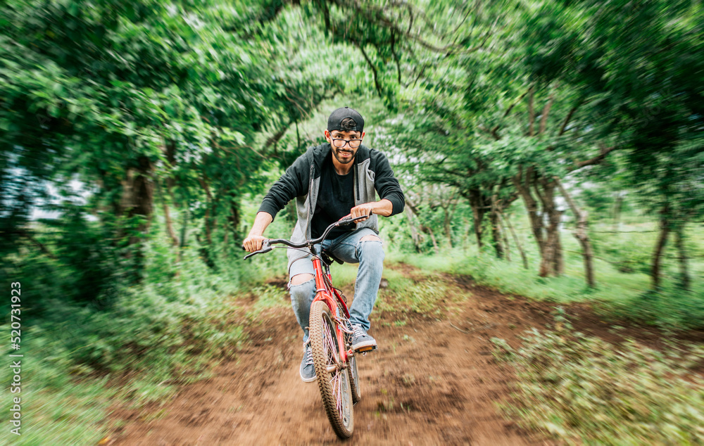 Portrait of a guy in cap riding a bike on a country road, Person riding a bike in the countryside, Bicyclist person on his bike on a country road forest. Teenage guy riding a bike in the countryside Portrait of a guy in cap riding a bike on a country road, Person riding a bike in the countryside, Bicyclist person on his bike on a country road forest. Teenage guy riding a bike in the countryside