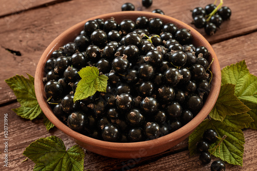 Berries of blackcurrant. Blackcurrant in a bowl isolated on a wooden background. Close-up.