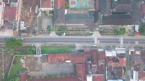 highway on the middle of population decent housing in central java. Aerial view of housing which are divided by road taken from drone camera in Magelang, Indonesia. 4K videos. photo