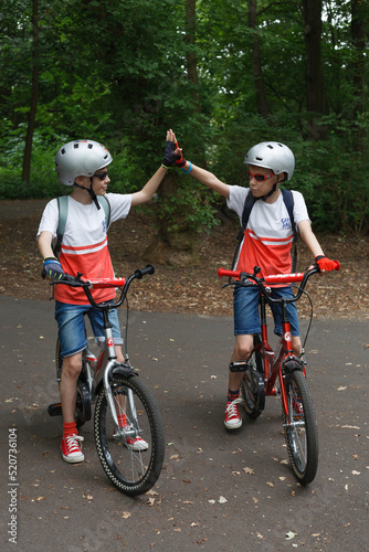 Two boys on bikes giving each other a high five