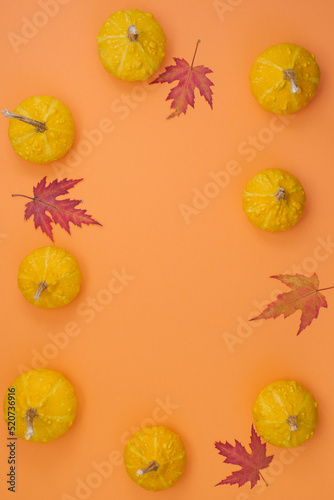Festive autumn decor of pumpkins and fallen leaves on a light background. Flat lay autumn composition with copy space. Thanksgiving or Halloween day concept.
