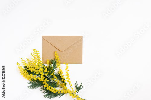 Craft envelope and mimosa branch on a white background Flat lay and copy space