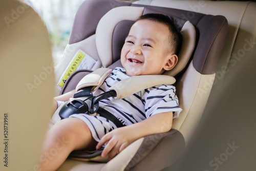 Cute baby boy smiling in safety car seat. Happy baby on the car. Child transportation safety concept. © Oulaphone