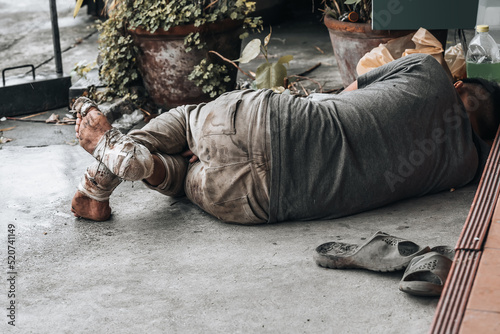 Homeless man sleeps on the street in front of the shop and begging for help and money. Problems of big modern cities