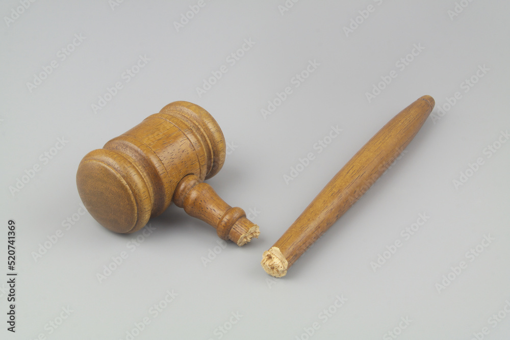 Broken wooden judge gavel on gray background. Concept of iniquity, injustice and lawlessness. Broken wooden judge gavel on gray background. Concept of iniquity, injustice and lawlessness.