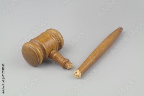 Broken wooden judge gavel on gray background. Concept of iniquity, injustice and lawlessness. photo