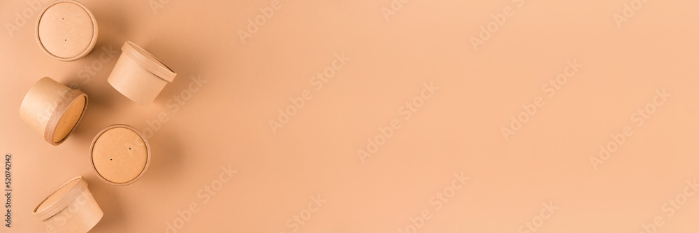 Banner with paper food containers, cup with paper cap over light brown background with copy space, mockup image. Sustainable food packaging. Monochrome Banner with paper food containers, cup with paper cap over light brown background with copy space, mockup image. Sustainable food packaging. Monochrome