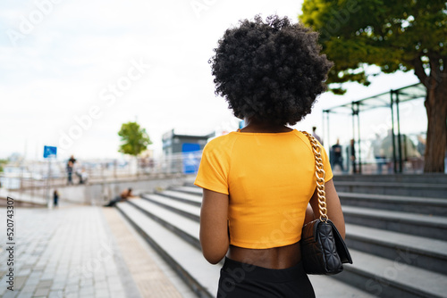 Smiling fashionable afro american woman walking on city street