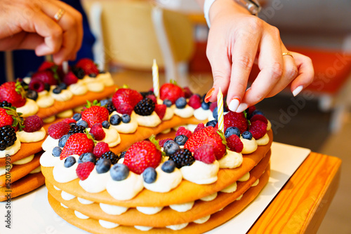candles put on the cake with berries in the form of the number ten.