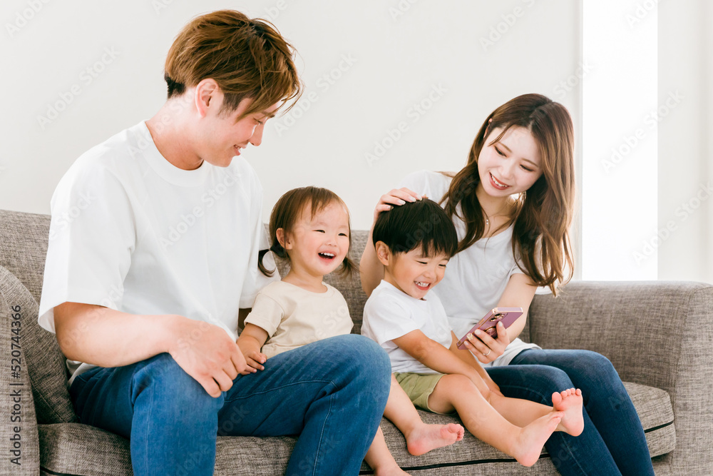 家のリビングでスマホを見る日本人家族（親子）
