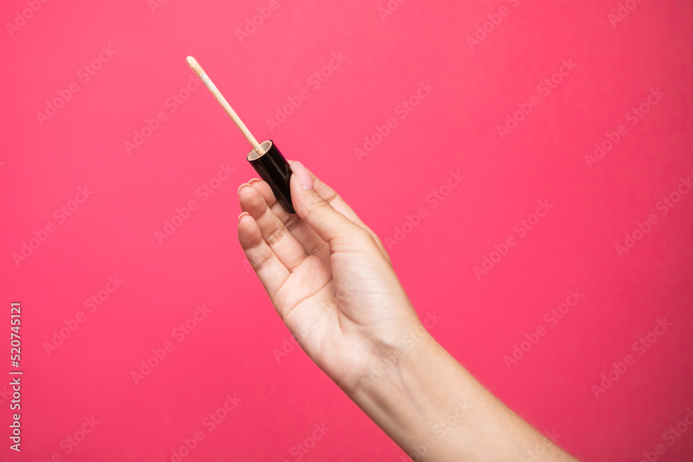 Woman hands holding concealer applicator isolated on pink background Woman hands holding concealer applicator isolated on pink background