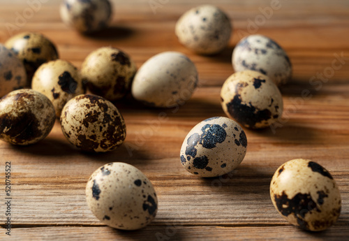 Many quail eggs placed against a wooden background.