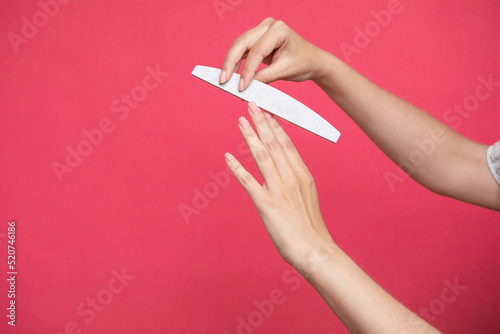 Woman hands manicure with nail file isolated on pink background