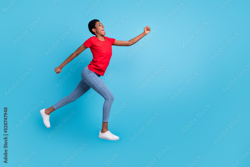 Full size photo of sportive energetic person jump rush look empty space isolated on blue color background Full size photo of sportive energetic person jump rush look empty space isolated on blue color background