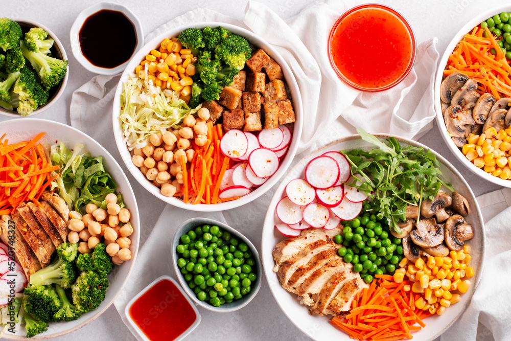 Plates with vegan buddha bowl and chicken buddha bowl with sauces on table, top view