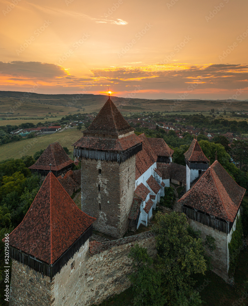 Aerial view with Viscri fortified church from Transylvania, Romania, during a beautiful summer sunrise. Travel to landmarks of Romania.