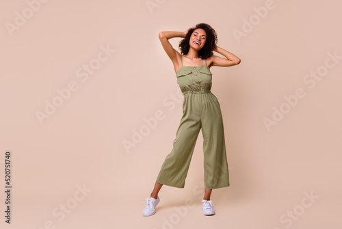 Full length photo of lovely young lady overjoyed soft curly hair product promo wear trendy khaki outfit isolated on beige color background