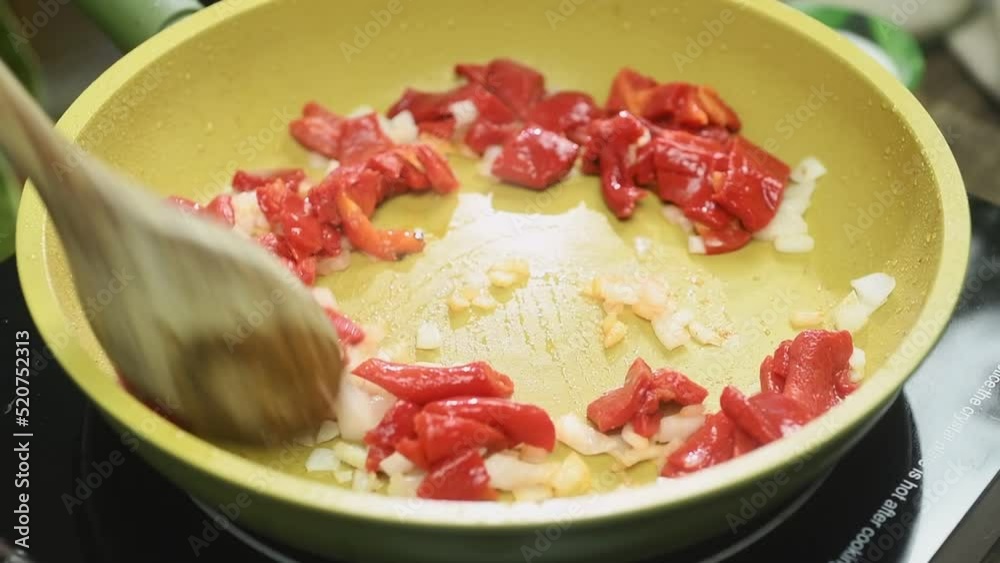 The cook stirs the roasted red peppers with garlic and onion in the pan.
The cook stirs the roasted red peppers with garlic and onion in the pan.