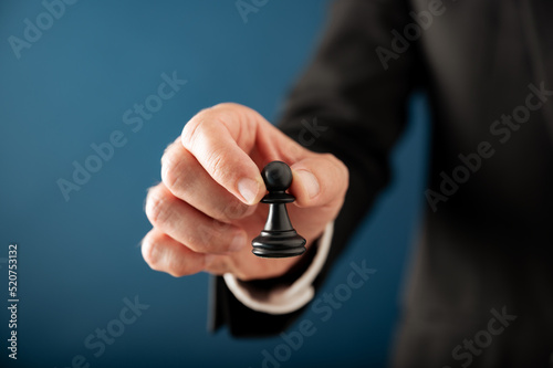 Closeup view of hand of a businessman holding black chess pawn piece