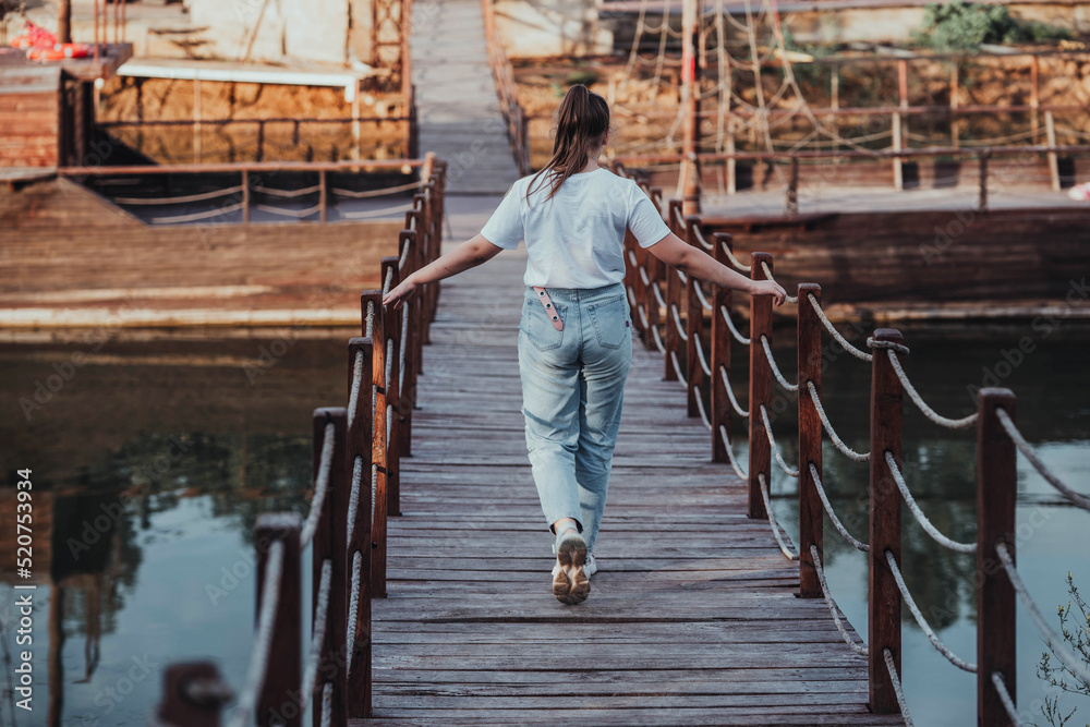 girl walking on a bridge in a natural park girl walking on a bridge in a natural park