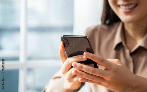 Smiling young woman hand holding smartphone with using social media on internet.
