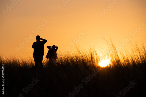 Silhouettes, a young couple is photographed at sunset in the tall grass