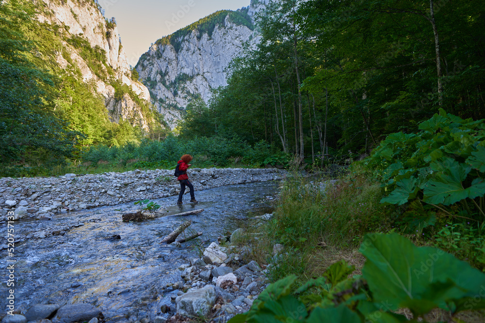 Woman hiker crossing river