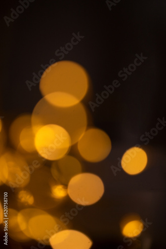 Golden bokeh on dark background. Abstract, Festive, Christmas and party design with bright circles particles.