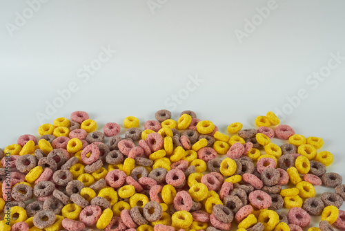 Rainbow cornflakes rings close-up on white background. The concept is ready-made breakfasts for children.