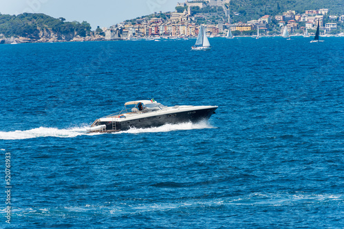 Blue and white luxury speedboat or yacht in motion on Mediterranean sea in front of the Porto Venere or Portovenere, Gulf of La Spezia, UNESCO world heritage site, La Spezia, Liguria, Italy, Europe.