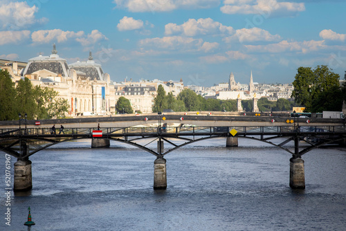Photograph of the Pont des Arts over the Seine river in Paris, dividing the Parisian city in two parts. Creating a beautiful scenery with the bridge and the Parisian city in the background. photo