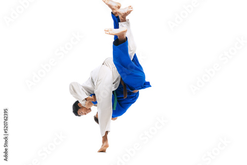 Studio shot of two men, professional judo athletes training, practising throws isolated over white background photo