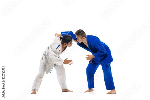 Studio shot of two men, professional judo, combat sport athletes training isolated over white background