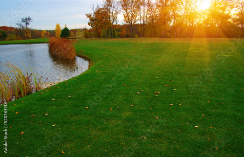 Autumn landscape with lake, green grass and colourful trees