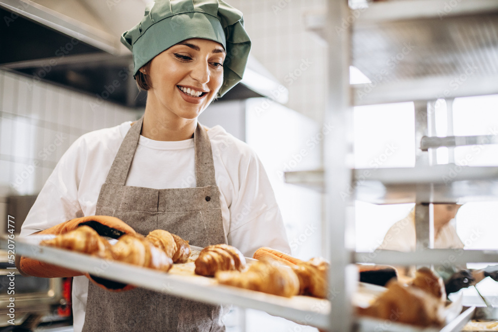 Female baker at the kitchen holding freshly baked croiisants Female baker at the kitchen holding freshly baked croiisants