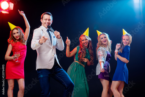 Party and celebration. Group of six happy smiling friends having fun together, singing karaoke in the club.