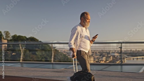 Happy senior man walks on footbridge with electric unicycle photo