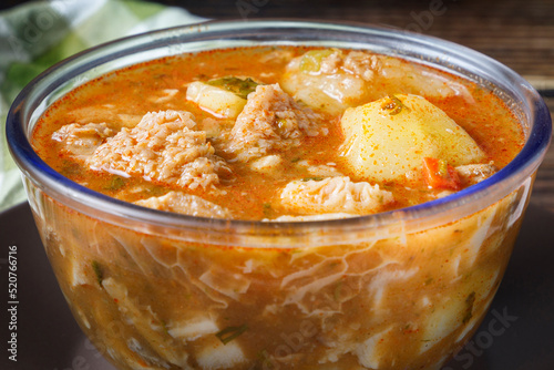 Colombian traditional tripe soup in a glass bowl on wooden table