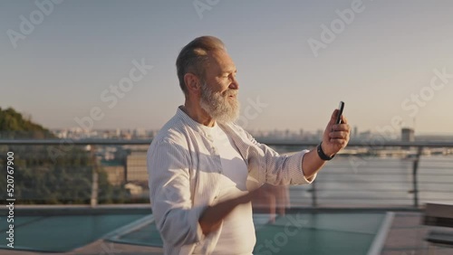 Bearded pensioner enjoys talking to friend on video call photo