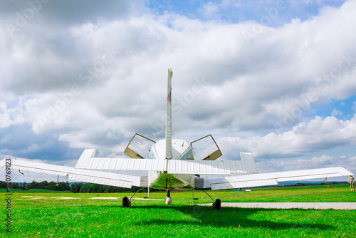 Small airplane in the background on a green field under the blue sky.