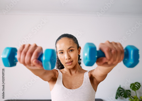 Obraz na plátně A serious young woman lifts small weights to get strong at home