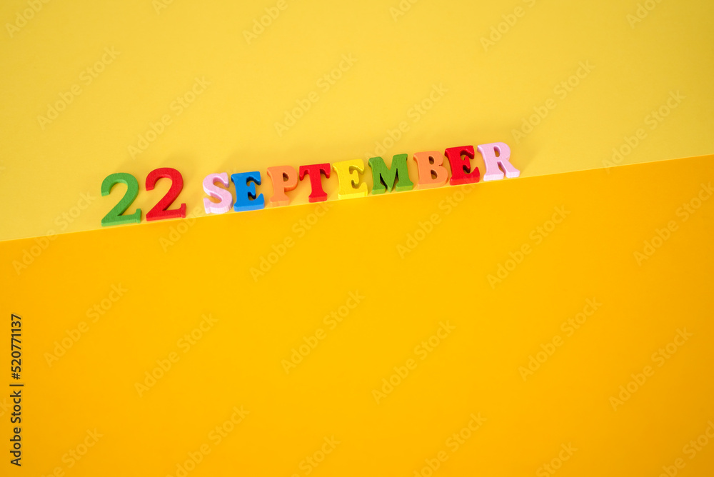 September 22 on a yellow and paper background with wooden letters and numbers in different colors. September 22 on a yellow and paper background with wooden letters and numbers in different colors.