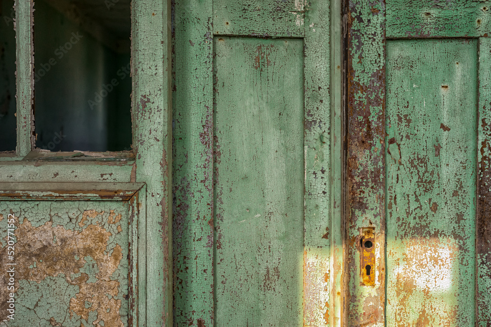 Vintage background shabby upper part of an old door and broken window with green peeling paint