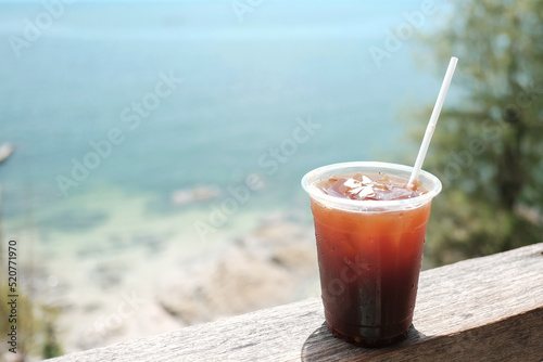 iced coffee and sea, Iced black coffee americano in take away cup (plastic glass) on the beach background
