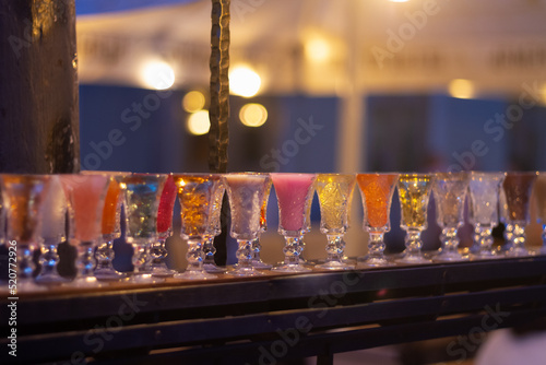 Glass stacks are filled with different drinks as an advertisement in a drinking establishment, a bar on the street